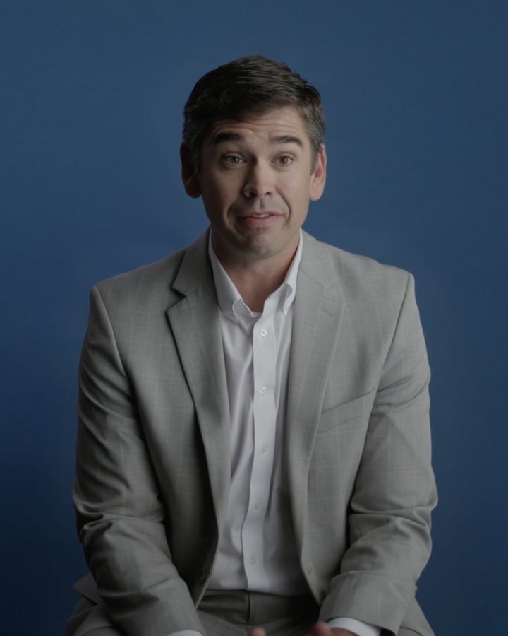 Interview subject in a suit against a deep blue backdrop